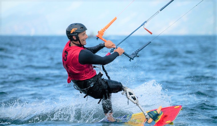 Un homme avec une prothèse de jambe se tient sur sa planche de kitesurf